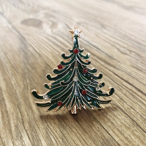 May include: A gold-tone Christmas tree ornament with green enamel and red and clear rhinestones.