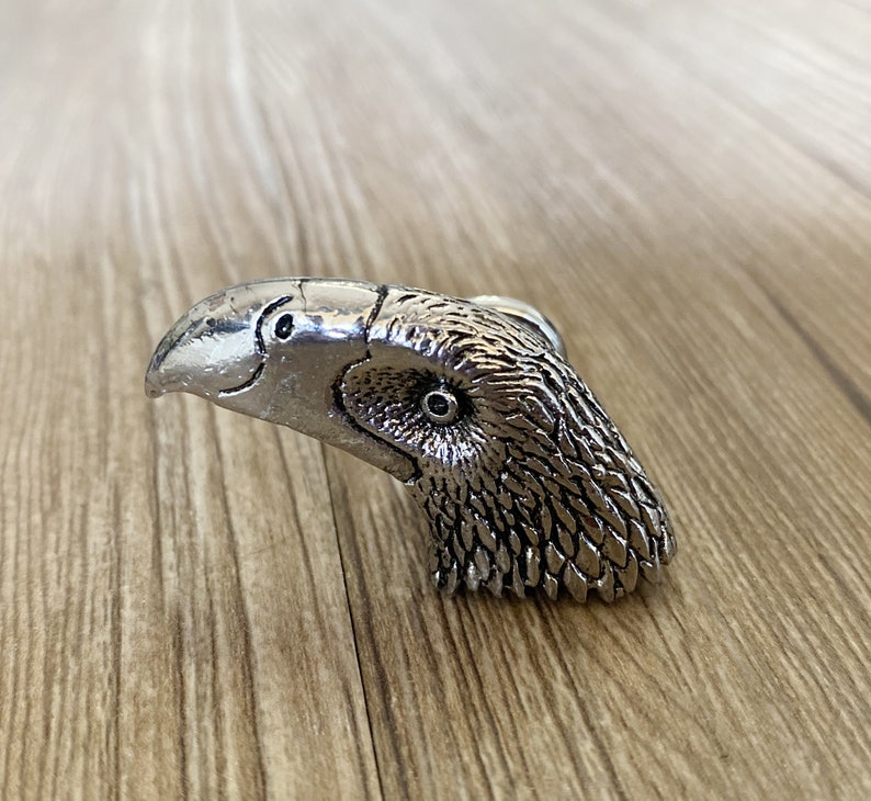 May include: A silver eagle head door knob with detailed feathers and a realistic eye.