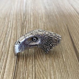 May include: A silver eagle head ring with detailed feathers and a realistic eye.