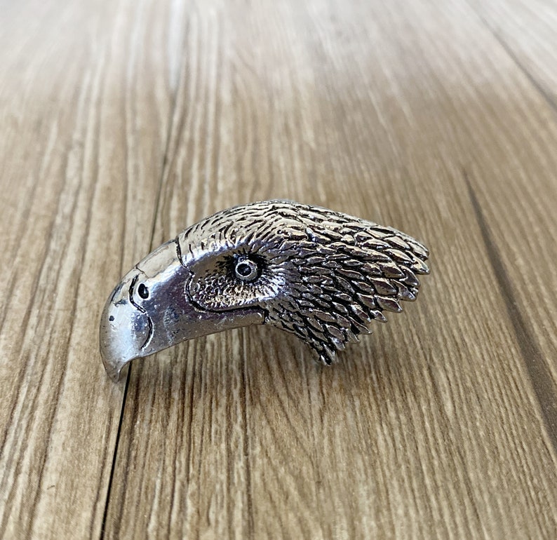 May include: A silver eagle head ring with detailed feathers and a realistic eye.