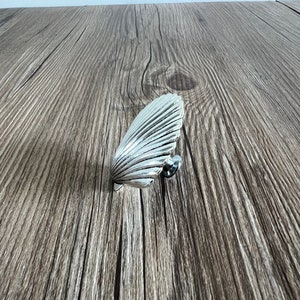 May include: Silver-toned seashell-shaped cabinet knob with a textured surface.