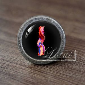 Può includere: Un pomello argentato con sfondo nero e un design astratto colorato. Il pomello è rotondo e ha un bordo rialzato.