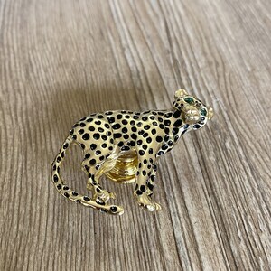 Peut inclure: Bouton de porte en forme de gu&eacute;pard en or. Le gu&eacute;pard est noir et or avec des yeux verts.