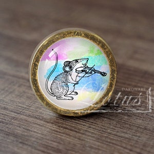 May include: A round, brass-colored knob with a colorful watercolor background and a black and white illustration of a mouse playing a violin. The knob is perfect for adding a whimsical touch to furniture.