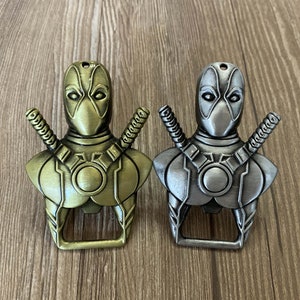 May include: Two metal bottle openers shaped like Deadpool. One is gold and the other is silver.