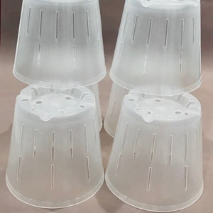 May include: Six clear plastic plant pots with drainage holes. The pots are stacked in two rows of three. The pots are all the same size and shape.