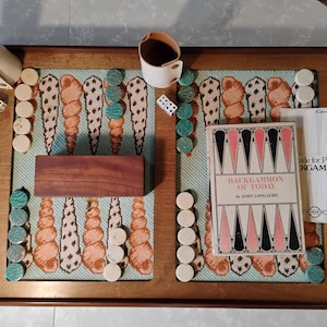 Puede incluir: Una taza de cerámica blanca con un asa negra y el texto "But First, Coffee" en negro, con una fuente de estilo manuscrito. La taza está sobre una superficie blanca.