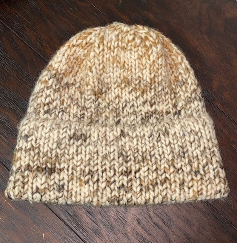May include: A beige and brown knit beanie hat with a textured knit pattern.