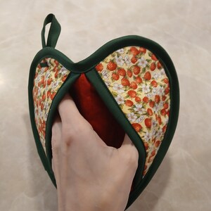 Pu&ograve; includere: Un guanto da forno a forma di cuore verde e rosso con un motivo a fragole e fiori. Il guanto da forno ha un anello per appenderlo.