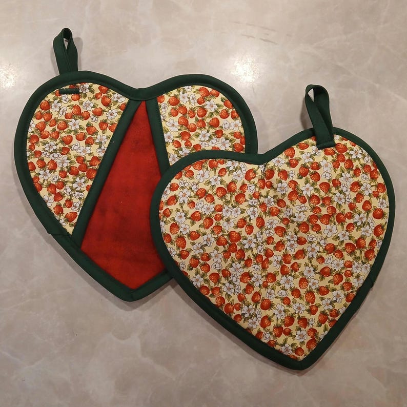 Pu&ograve; includere: Due presine a forma di cuore con bordino verde. Una presina &egrave; rossa con un motivo di fragole bianche e verdi. L'altra presina &egrave; gialla con un motivo di fragole bianche e verdi.