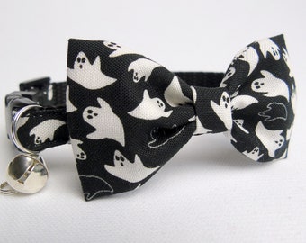 May include: Black cat collar with a white ghost pattern and a matching bow tie. The collar has a silver bell and a black plastic buckle. The bow tie is approximately 3 inches wide.