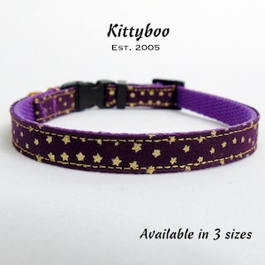 Puede incluir: Collar de gato morado con estrellas doradas. El collar est&aacute; hecho de tela y tiene una hebilla de pl&aacute;stico. El texto "Kittyboo Est. 2005" est&aacute; impreso en el collar. El texto "Disponible en 3 tama&ntilde;os" est&aacute; impreso debajo del collar.