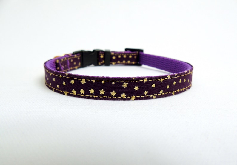Puede incluir: Collar para mascotas morado con estampado de estrellas doradas. El collar tiene una hebilla de pl&aacute;stico negra.