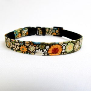 May include: A green, black and orange floral patterned dog collar with a black buckle.