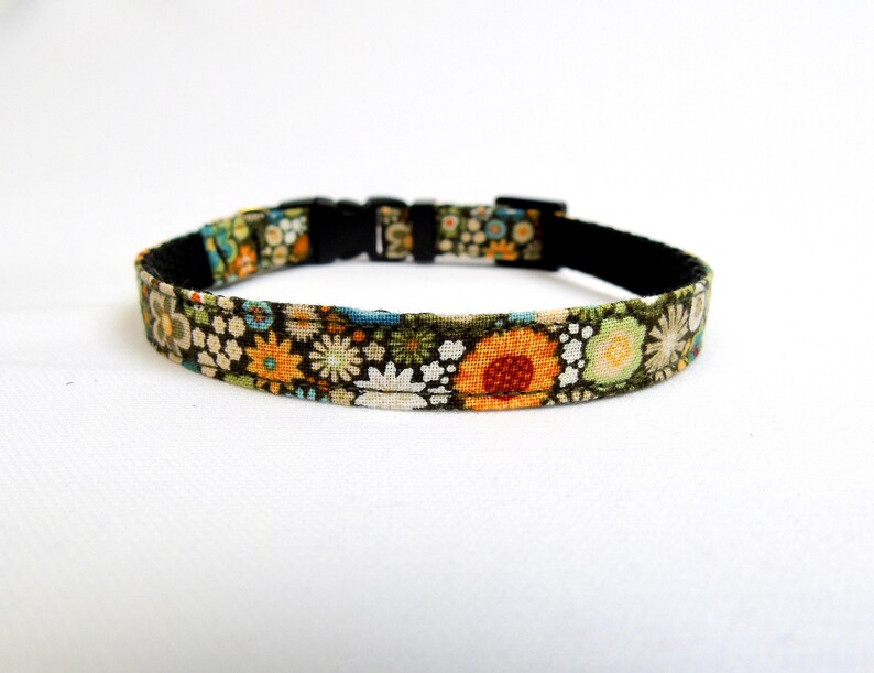 May include: A green, black and orange floral patterned dog collar with a black buckle.