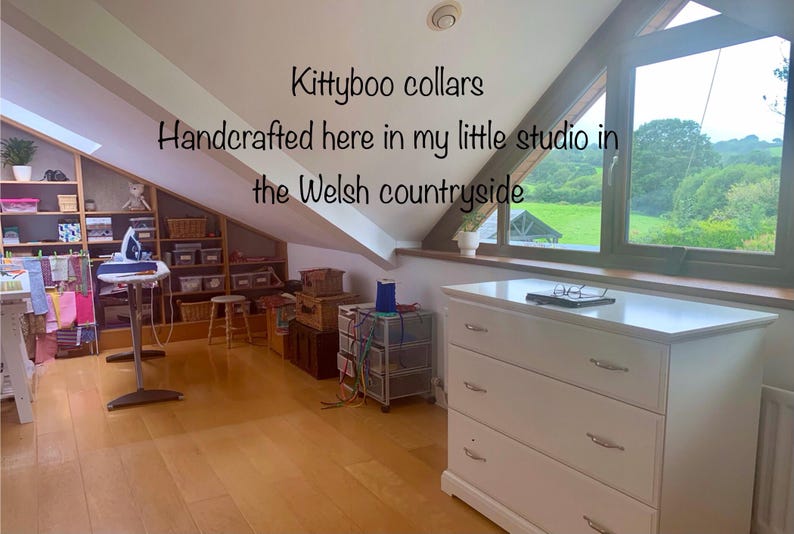 Puede incluir: Una c&oacute;moda blanca con tres cajones y tiradores plateados. La c&oacute;moda est&aacute; en una habitaci&oacute;n con una ventana que da a un campo verde. El texto "Kittyboo collars Handcrafted here in my little studio in the Welsh countryside" es visible en la imagen.