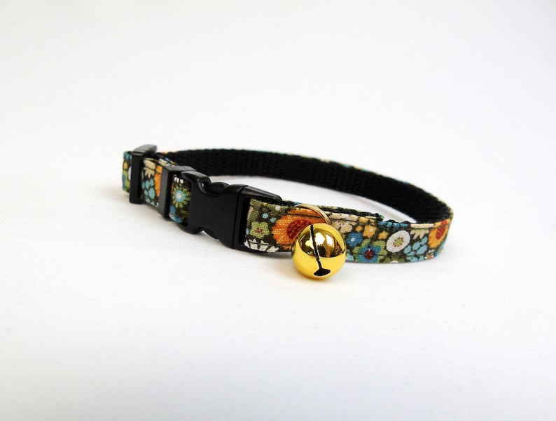 May include: A floral patterned cat collar with a black buckle and a gold bell.