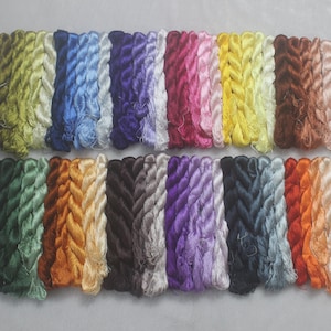 May include: An assortment of colorful embroidery floss in various shades, including green, blue, purple, pink, yellow, and brown. The floss is neatly arranged in bundles, showcasing a range of hues for crafting and textile projects.