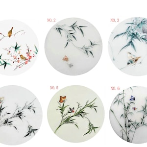 May include: Six round embroidery hoops with different designs. The designs include birds, butterflies, and bamboo branches. The hoops are all white with a light green background.