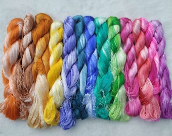 May include: Assortment of 10 spools of colorful silk thread. The thread is twisted and has a gradient of color from one end to the other. The colors are orange, yellow, blue, green, pink, and purple.