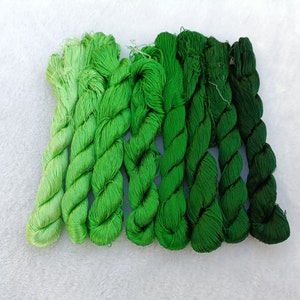 May include: A set of eight spools of green embroidery floss, arranged in a gradient from light green to dark green.