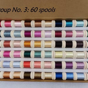 May include: A box containing 60 spools of thread in various colors. The spools are arranged in rows, with colors ranging from pinks and reds to blues and greens. The text "Group No. 3: 60 spools" is visible on the box.