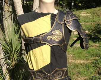 May include: A black and gold leather armor set with a wolf design. The armor includes a shoulder piece, a belt, and a chest piece.
