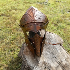 May include: A brown leather helmet with a textured design and metal accents. The helmet has a visor and is decorated with rivets.