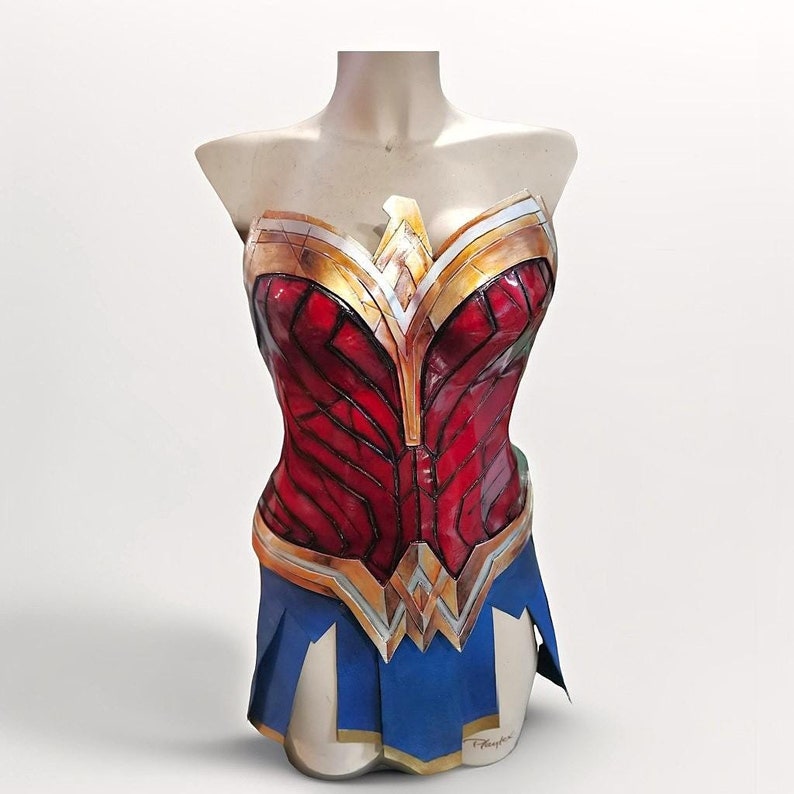 Op de afbeelding: Een rood, goud en blauw Wonder Woman kostuum met een bustier top en een rok. De bustier heeft een geometrisch patroon en de rok heeft een gouden rand.