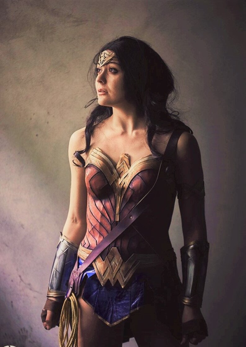Op de afbeelding: Een vrouw verkleed als Wonder Woman, draagt een rood, goud en bruin kostuum met een gouden tiara en armbanden. Ze kijkt omhoog en naar rechts.