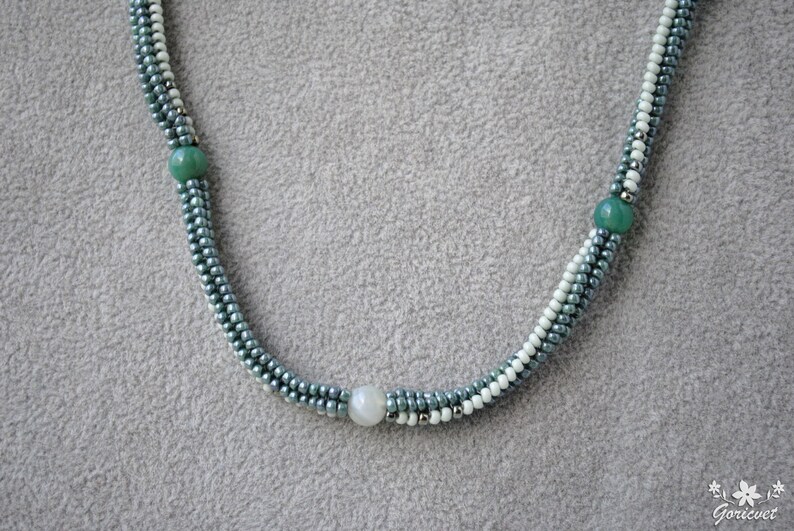 May include: A multi-strand necklace with green and white beads. The necklace has a silver-toned metal clasp.