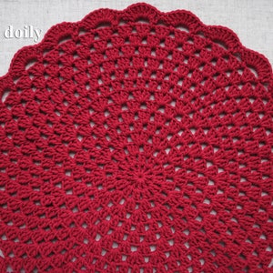 Pu&ograve; includere: Un centrino all'uncinetto rosso con un design circolare. Il centrino &egrave; realizzato con un filo sottile e ha un aspetto delicato e traforato. Il testo "Moon doily" &egrave; visibile nell'angolo in alto a sinistra dell'immagine.