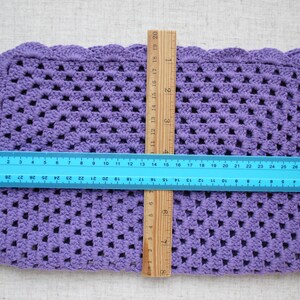 May include: A purple crocheted square placemat with scalloped edges. The placemat measures approximately 12 inches by 18 inches.