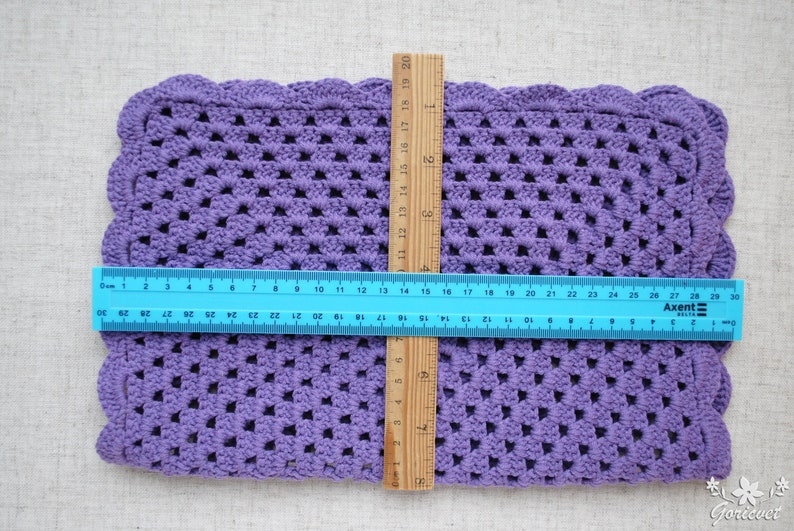 May include: A purple crocheted square placemat with scalloped edges. The placemat measures approximately 12 inches by 18 inches.