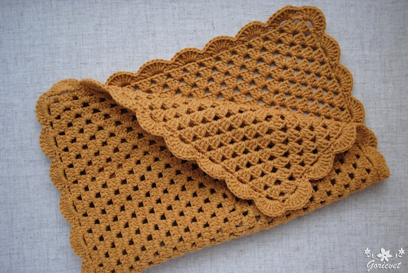 May include: A crocheted baby blanket in a mustard yellow color with a scalloped edge.