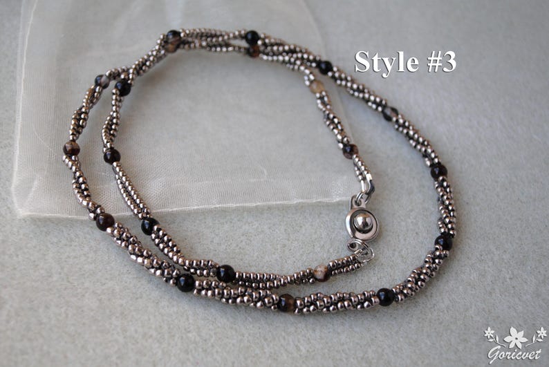 Op de afbeelding: Een zilveren en zwarte kralenketting met een magneetsluiting. De ketting is gelaagd en heeft een subtiele glans. Style #3