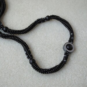May include: A black beaded necklace with a large, round, black hematite pendant.