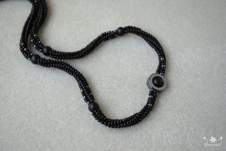 May include: A black beaded necklace with a large, round, black hematite pendant.