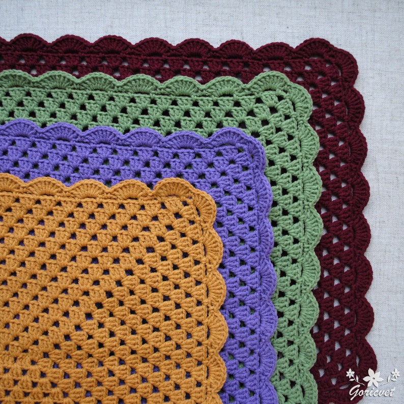 May include: Four crocheted squares in different sizes and colors, including burgundy, green, purple, and orange. The squares have a scalloped edge and are made with a simple stitch pattern.