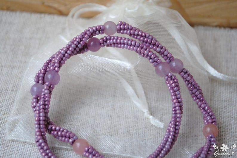Puede incluir: Un collar de doble cadena hecho de peque&ntilde;as cuentas moradas y cuentas m&aacute;s grandes de color morado y rosa.