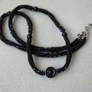 May include: A black beaded necklace with a silver clasp and a black circular pendant.
