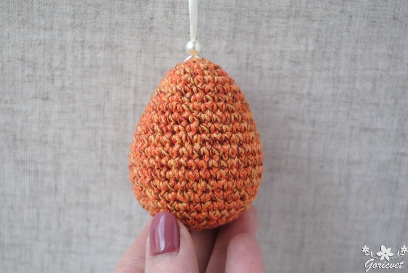 Pu&ograve; includere: Un ornamento a forma di uovo in crochet arancione e giallo. L'uovo &egrave; realizzato con un punto testurizzato e ha una lucentezza sottile.