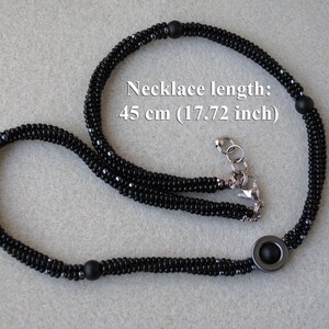 May include: Black beaded necklace with a silver clasp and a round black pendant. The necklace is 45 cm (17.72 inches) long.