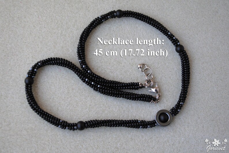 May include: Black beaded necklace with a silver clasp and a round black pendant. The necklace is 45 cm (17.72 inches) long.