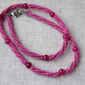 Puede incluir: Un collar de cuentas rosadas con cuentas rosadas m&aacute;s grandes espaciadas. El collar es de doble cadena y tiene un cierre plateado.