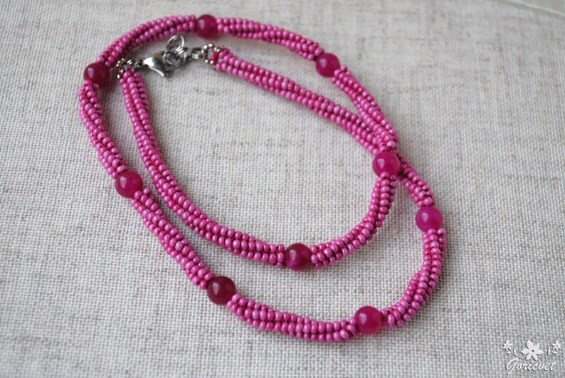 Puede incluir: Un collar de cuentas rosadas con cuentas rosadas m&aacute;s grandes espaciadas. El collar es de doble cadena y tiene un cierre plateado.