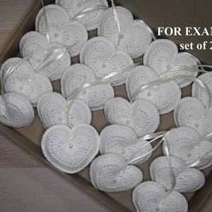 May include: A set of 20 white crocheted hearts with pearl beads and satin ribbon. FOR EXAMPLE set of 20.