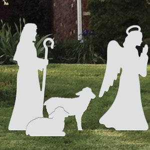 May include: White silhouette cutout of a shepherd with a staff and two sheep, and an angel with wings, standing on a green grassy lawn.