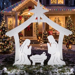 May include: A white outdoor nativity scene display featuring a stable structure topped with a large star. The silhouette includes two kneeling figures facing a central manger. The entire piece is constructed from flat, white panels and is positioned on a snowy lawn in front of a house decorated with Christmas lights.