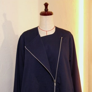 Puede incluir: Chaqueta azul marino de manga larga con cremallera diagonal. La chaqueta se exhibe en un maniquí. Presenta un cuello asimétrico y una cremallera plateada. Una prenda de vestir elegante.